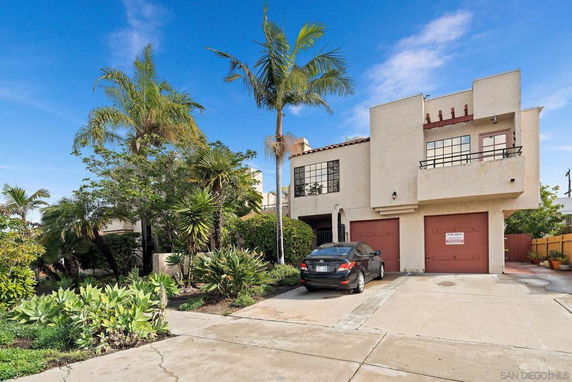 Front view of a two-story house with balconies and dual garage doors.