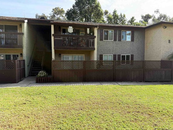 Front view of a two-story apartment building with balconies and fenced patio areas.
