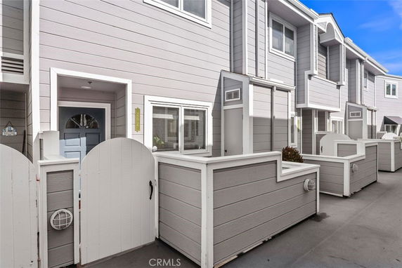 Front view of a multi-story townhouse with gray siding and white trim.