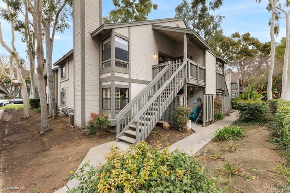 Front view of a two-story building with an exterior staircase and surrounding trees.