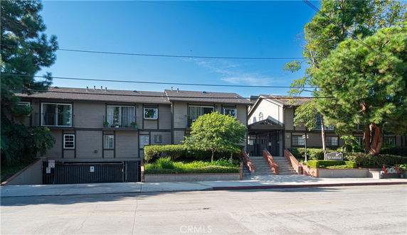 Front view of a multi-story building with a gated entrance and brick stairways.