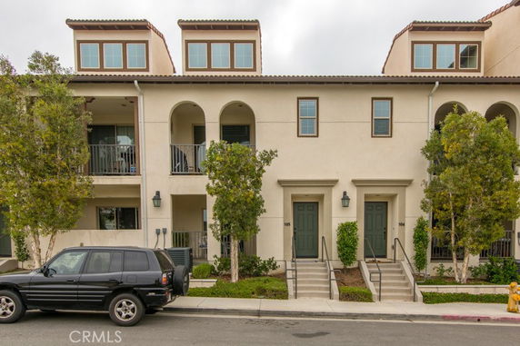 Front view of a multi-story townhouse with balconies and arched entrances.