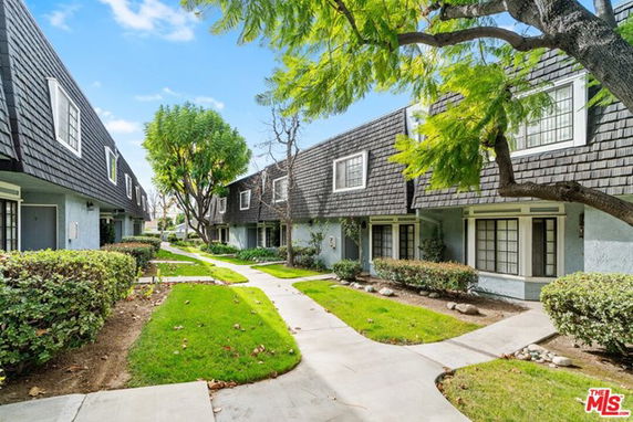 Front view of townhouses with shingled roofs and pathways.