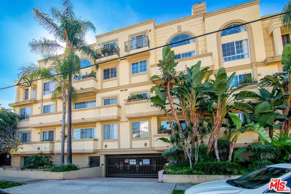 Front view of a multi-story building with balconies and a gated entrance.