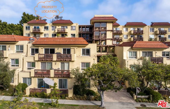 Front view of a multi-story residential building with balconies and red-tiled roofs.