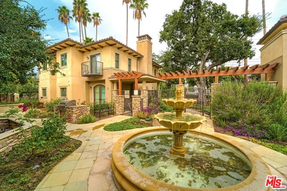 Front view of a two-story house with a fountain and balcony.