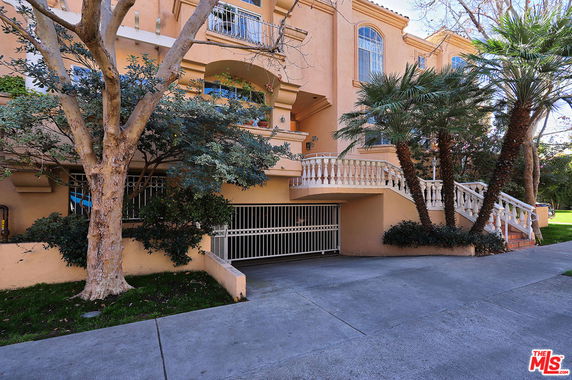 Front view of a multi-story building with a staircase and gated entrance.