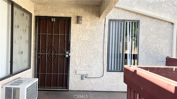 Front view of a residential building entrance with a metal door and barred windows.