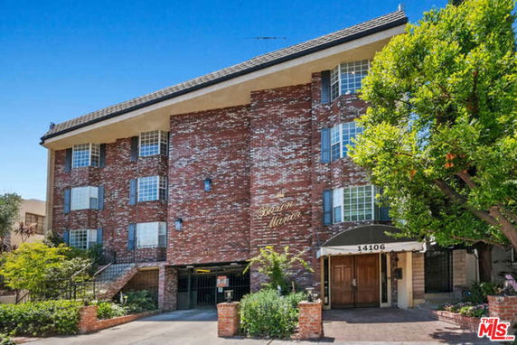 Front view of a multi-story brick building with gated entrance and multiple windows.