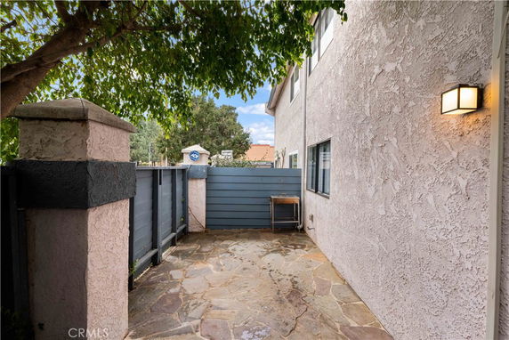 Side view of a building with stone pathway and fenced area.