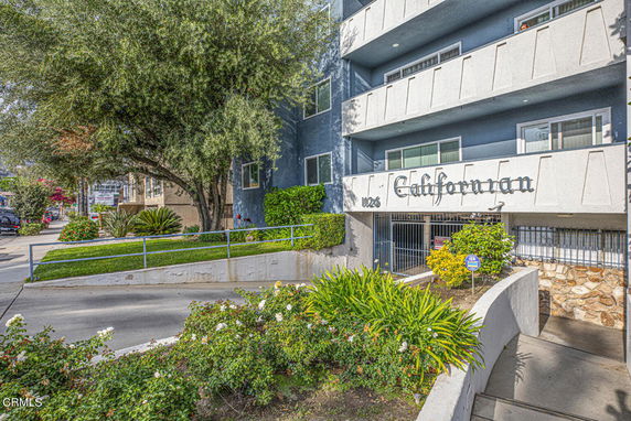 Front view of a multi-story building with balconies and a gated entrance.