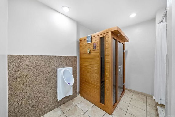 Indoor sauna room with wooden exterior next to a urinal.