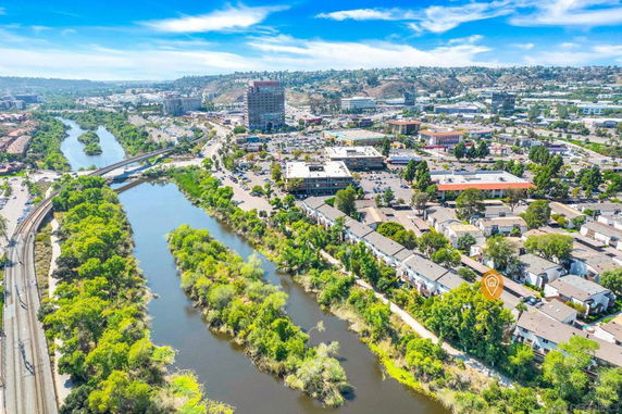 Aerial panoramic view of a river surrounded by urban buildings and greenery.