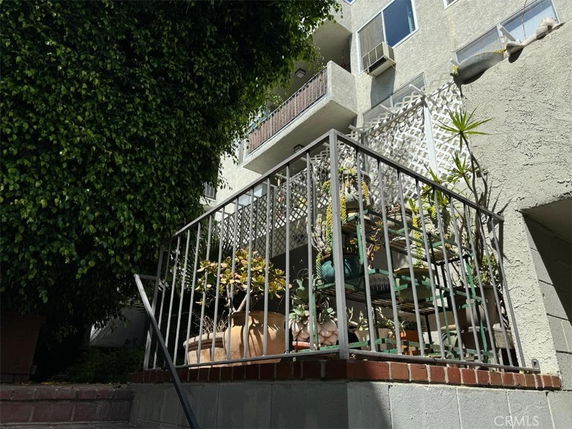 Front view of a multi-story building with balconies and plant decorations.