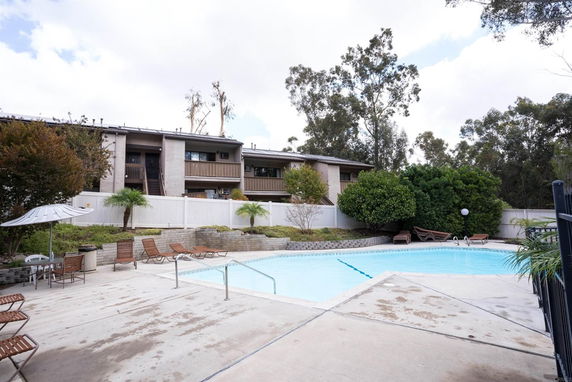 Outdoor swimming pool area with surrounding residential buildings.