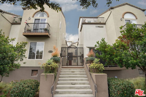 Front view of a multi-story house with balconies and a gated entrance.