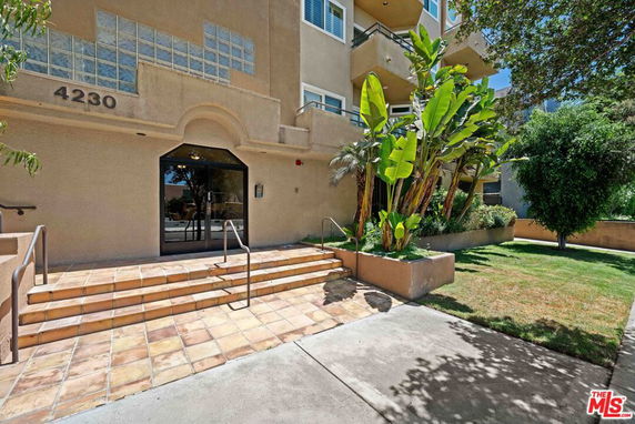 Front view of a multi-story building with stairs and entrance door.