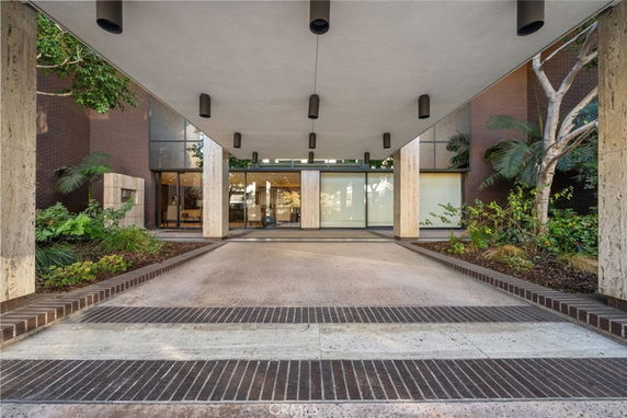 Front view of a modern building entrance with covered walkway and glass doors.