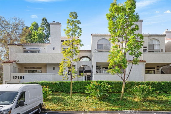 Front view of a multi-story residential building with balconies and arched windows.