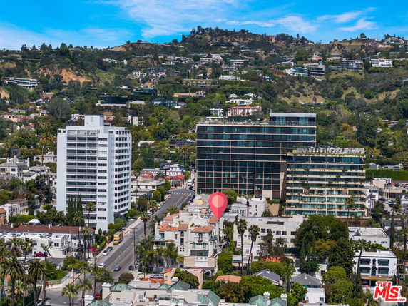 Panoramic view of cityscape with high-rise buildings and distant hills.