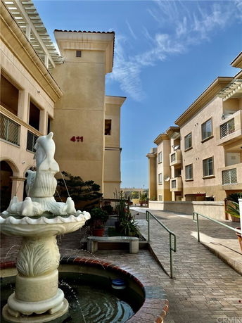 View of a multi-story residential building with balconies and decorative fountain.