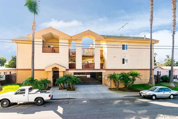 Front view of a three-story apartment building with a central entrance and balconies.