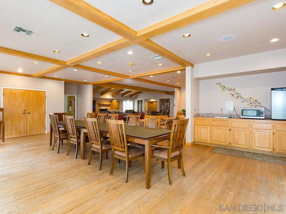 Recreational club house area with wooden furniture and kitchen amenities.