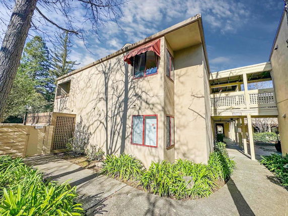 Front view of a two-story building with beige walls and red window frames.