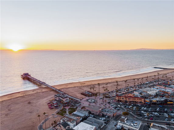 Panoramic view of a coastal area with a beach, pier, and surrounding buildings at sunset.