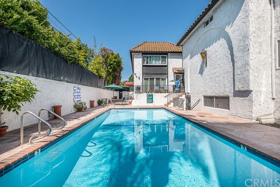 Outdoor swimming pool beside a two-story house.