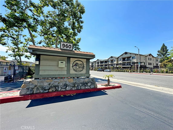 Front view of a multi-story residential building with a sign and trees in front.