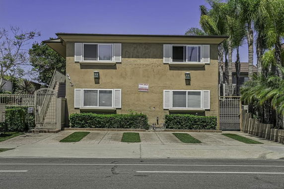 Front view of a two-story residential building with shutters and a gated entrance.