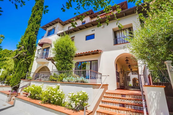 Front view of a multi-story house with a staircase and balcony.