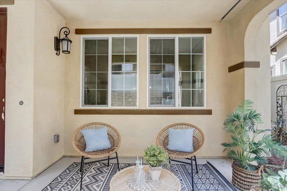 Front view of a house with a small seating area and large window.