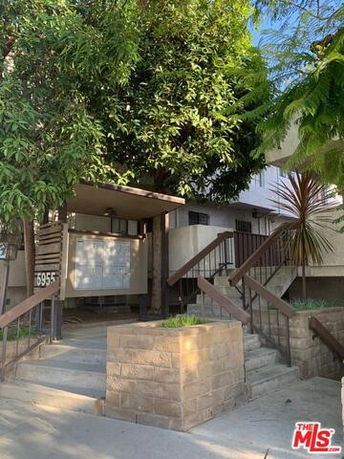Front view of a multi-story building with steps leading up to the entrance and trees surrounding the area.