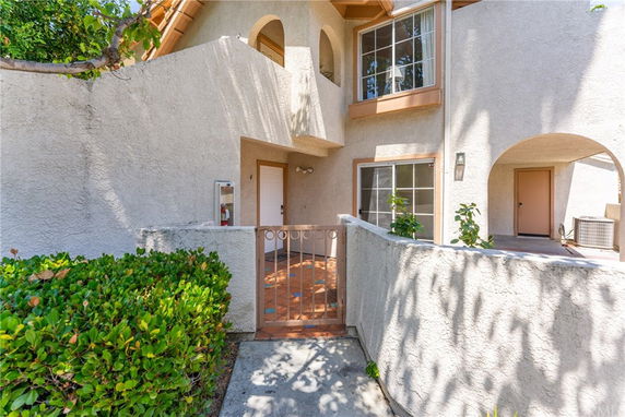 Front view of a house with stucco exterior and arched entryway.