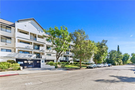Front view of a multi-story residential building with balconies and a gated entrance.