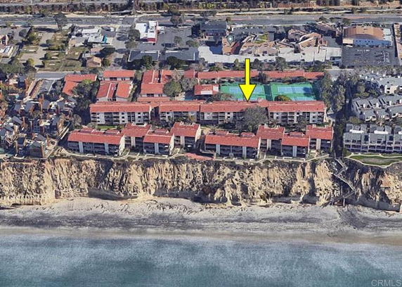 Aerial view of a coastal residential complex with red-roofed buildings.