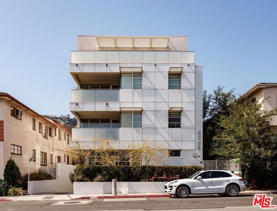 Front view of a modern multi-story building with a geometric facade and balconies.