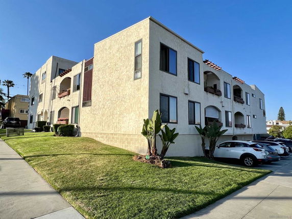 Front view of a multi-story residential building with balconies and several windows.