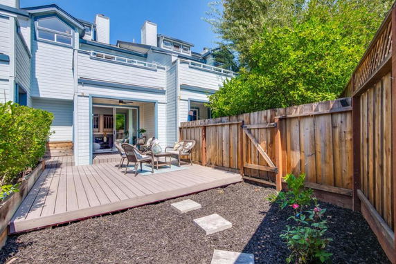Backyard view of a two-story house with a wooden deck and sliding doors.