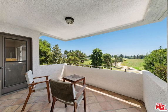 Balcony view of a landscaped area with trees and a grassy field.
