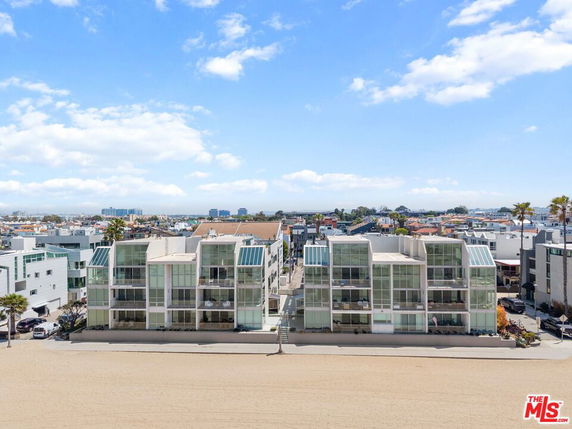 Front view of a modern beachfront building with large glass windows.
