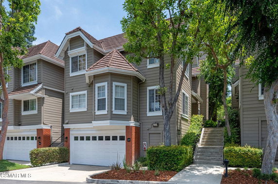 Front view of a multi-story townhouse with a double garage and gabled roof.
