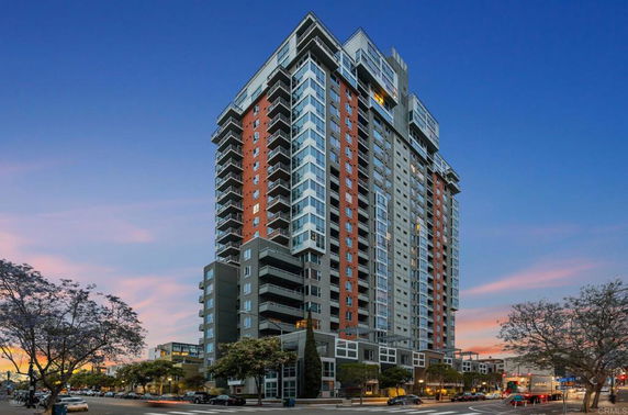 Front view of a multi-story residential building with balconies and windows at sunset.