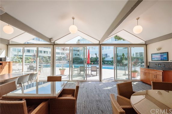 Interior view of a clubhouse with glass doors opening to a patio and swimming pool.