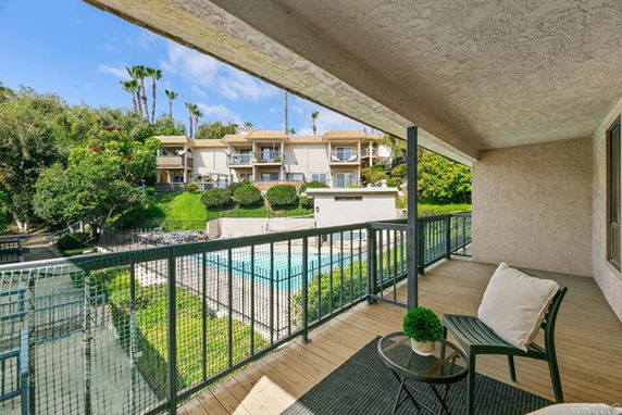 View from a balcony overlooking a swimming pool and surrounding buildings.