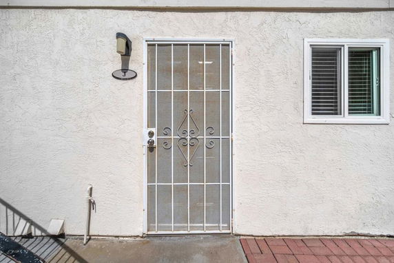 Front view of a building showing a security door and a window with blinds.
