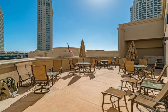 Rooftop area with chairs and tables, featuring high-rise buildings in the background.