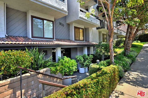 Front view of a multi-story residential building with balconies and a landscaped entrance.